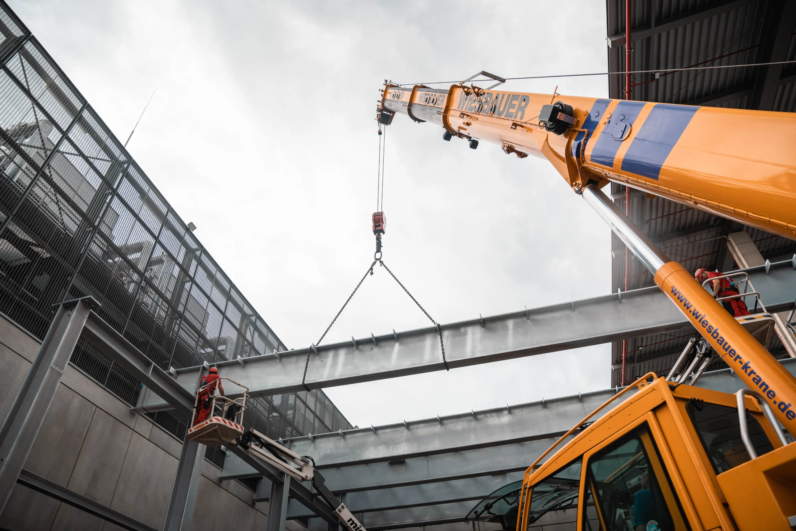 Ein Kran hebt eine DIN 1090 konforme Stahlkonstruktion auf einer Baustelle