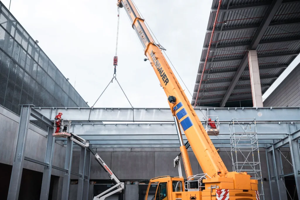 Ein Kran hebt einen Stahlträger einer Stahlkonstruktion