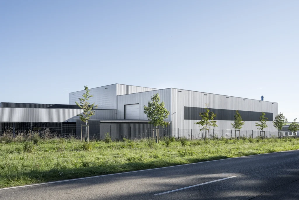Seitenansicht der Produktionshalle mit Metallfassade und Grünfläche