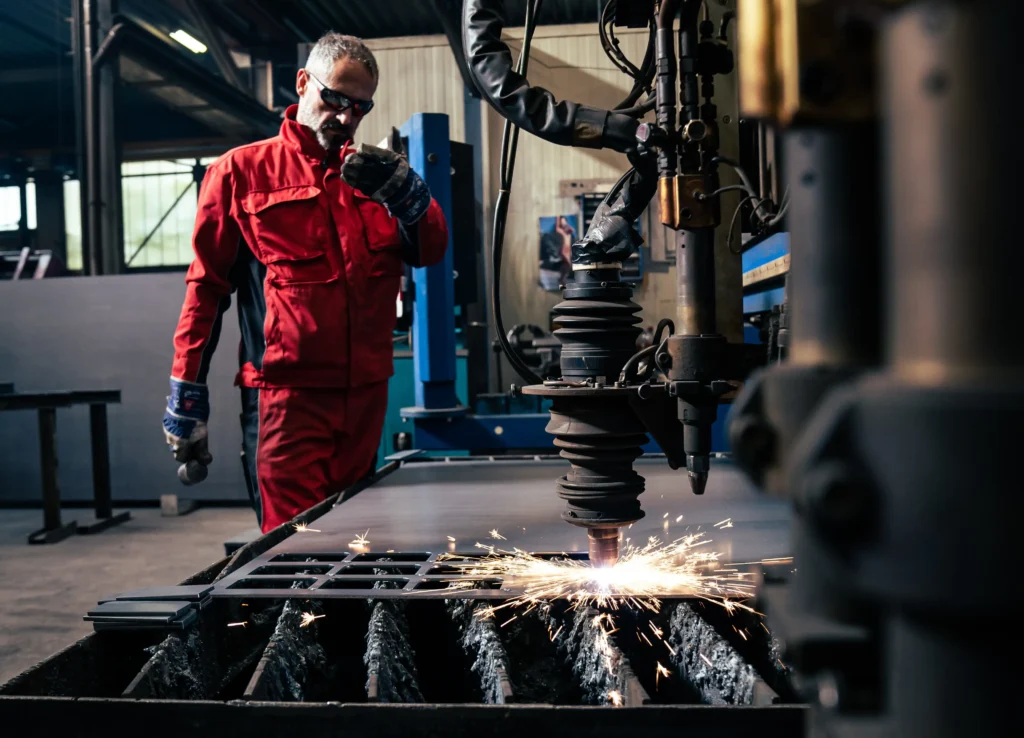 Brennschneiden mit Schutzkleidung Ein Mann mit Schutzkleidung, der den Brennschneidevorgang überwacht