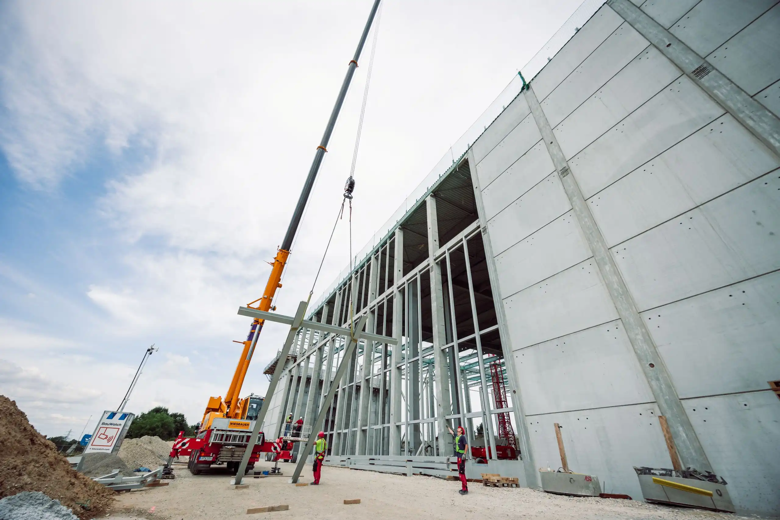 Ein Kran und Stahlbaumonteure bei der Montage eines Hallenbauprojektes