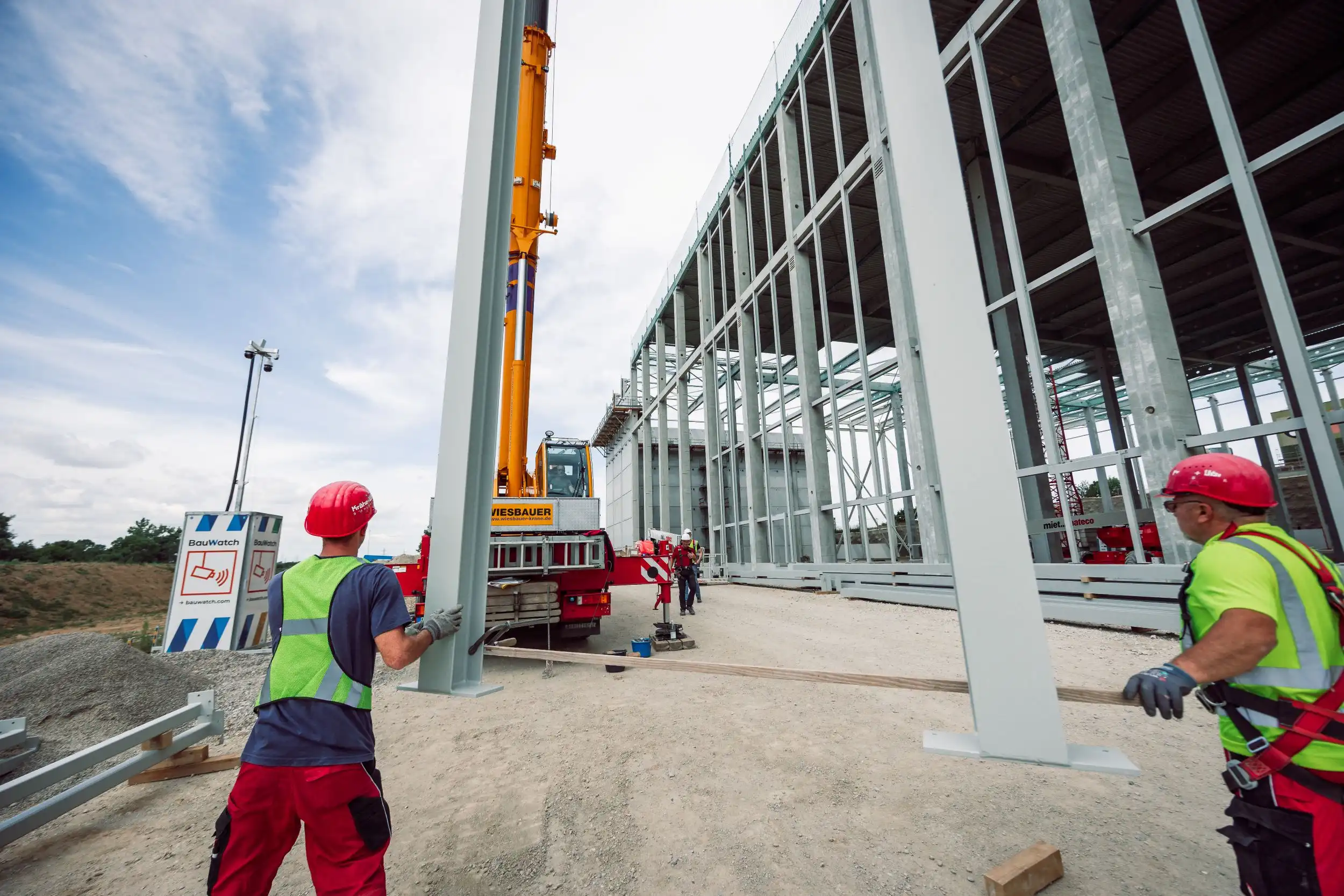 Montage einer Gewerbehalle mit Stahltragwerk und Kran auf einer Baustelle